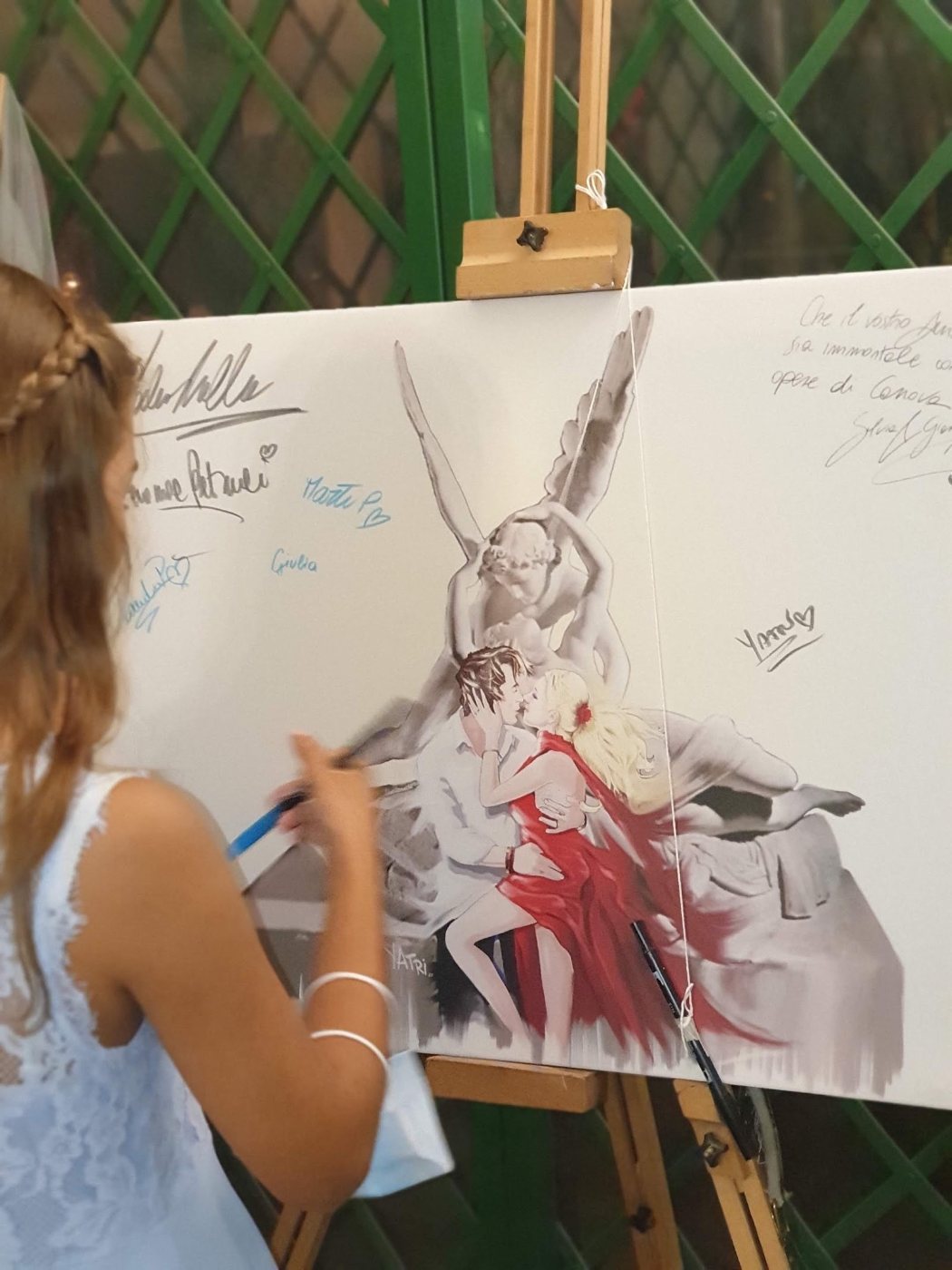 Invitata che scrive una dedica sul tableau dipinto da Yatri Arte